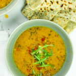 Tasty red lentil soup in a bowl with flatbreads