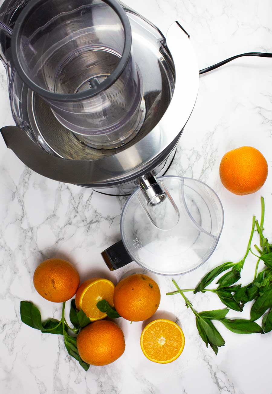 Juicer and oranges with basil 